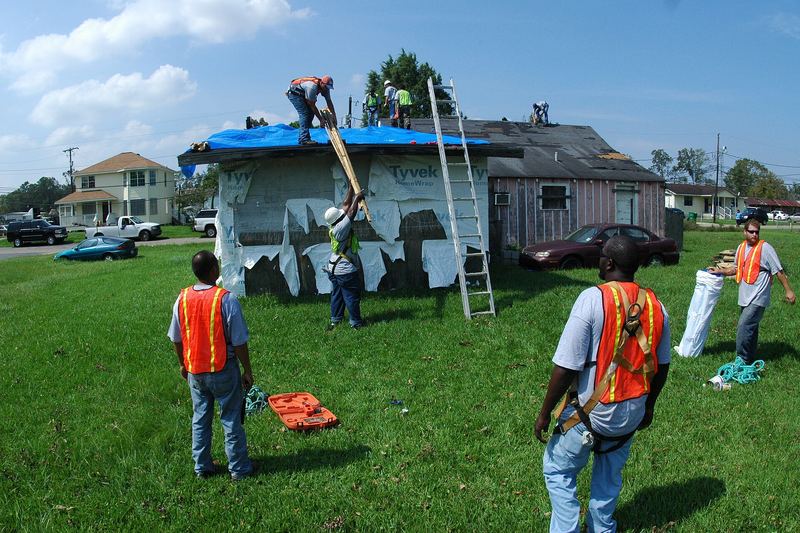 Installing a temporary blue roof tarp after a hurricane