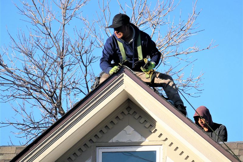 Roofers working on a steep gable roof